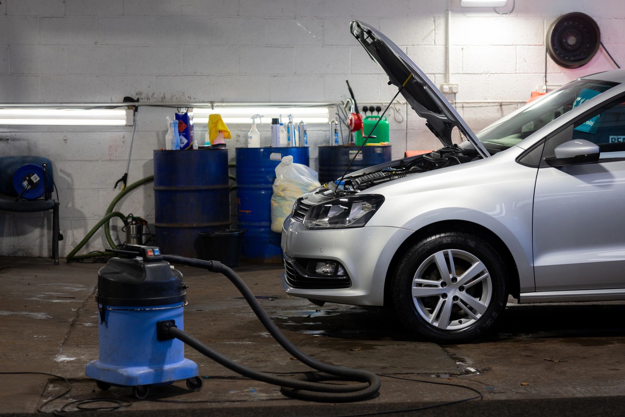 Car being serviced in a garage with hood open