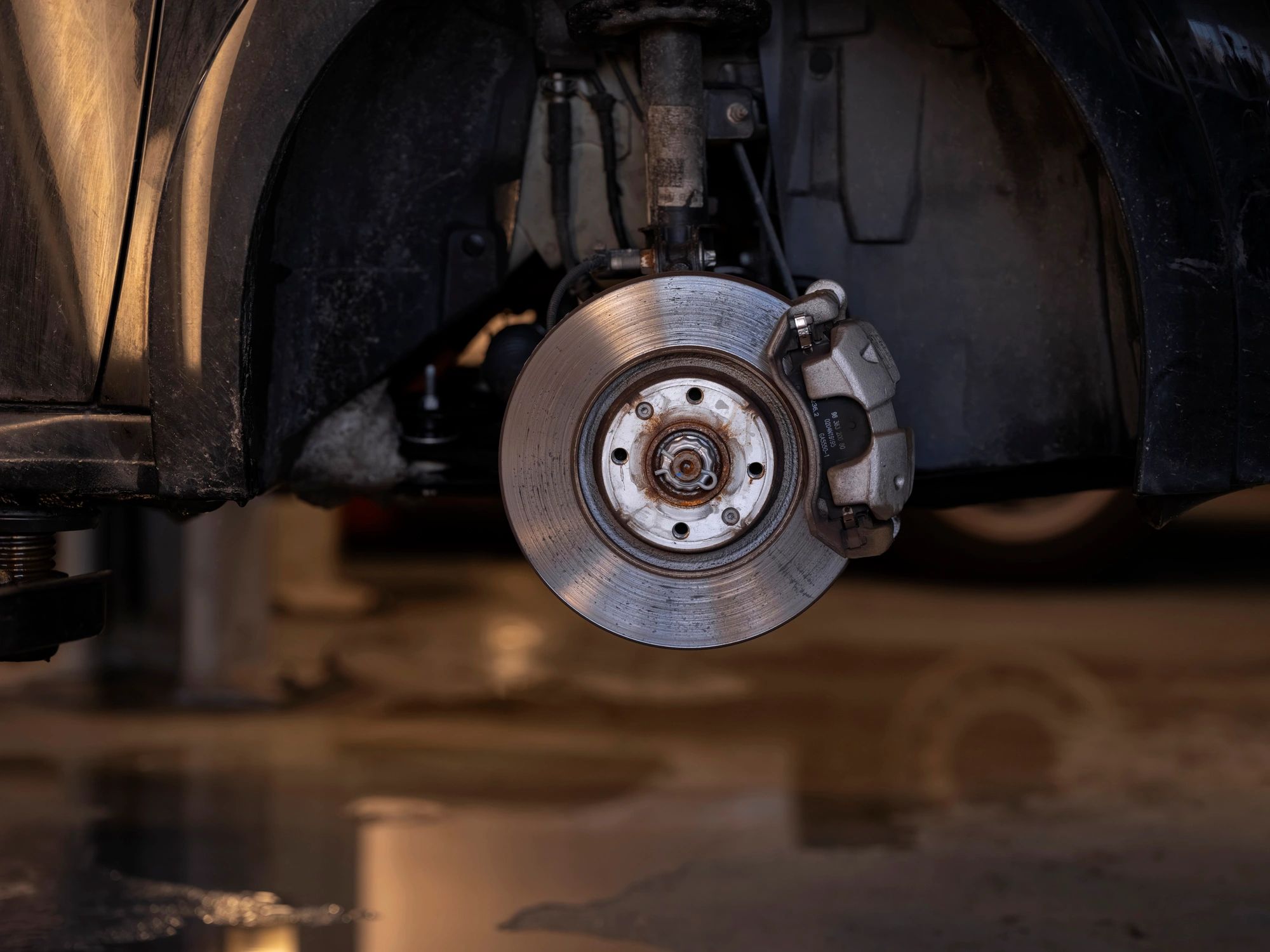 Close-up of a brake rotor and caliper assembly in a repair shop